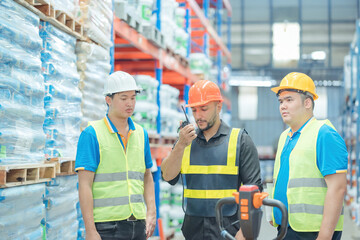 Warehouse workers in helmets checking goods and supplies on shelves with goods background in warehouse worker packing in a large warehouse in a large warehouse. Logistics industry concept..