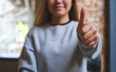 Closeup of a woman making and showing thumb up hand sign