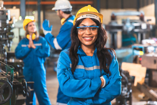 Young people worker in protective uniform operating machine at factory Industrial.People working in industry.Portrait of Female Engineer looking camera at work place.