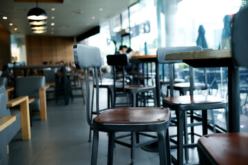 Closeup modern style of wooden chair on the metal structure in the coffee shop with blurred inside cafe in background