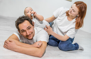 Fototapeta premium family in the studio or at home crawling on the floor with a baby. mom, dad, son play together