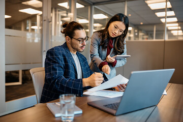 Multiracial coworkers going through business documents while working in office.