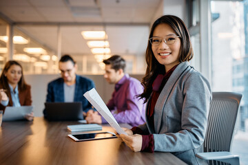 Happy Asian businesswoman on meeting in office looking at camera.