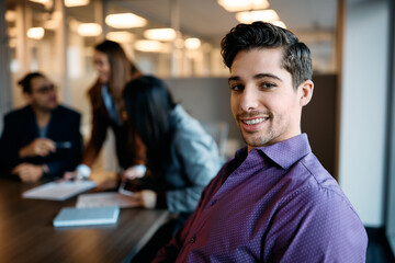 Young gay businessman having meeting with colleagues in office and looking at camera.