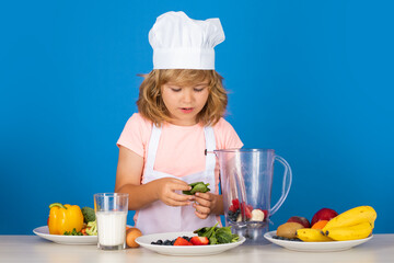 Portrait of chef child in cook hat. Cooking at home, kid boy preparing food from vegetable and fruits. Healthy eating.