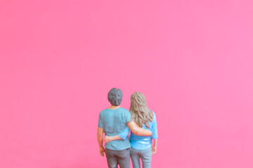 Miniature people man and woman in casual cloth standing together isolated on pink background , Valentine's day concept