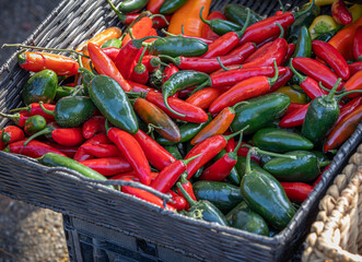 Red and green chili peppers in a basket for sale at the local farmer's market.