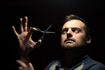 bearded man with scissors on a dark background