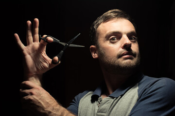 bearded man with scissors on a dark background