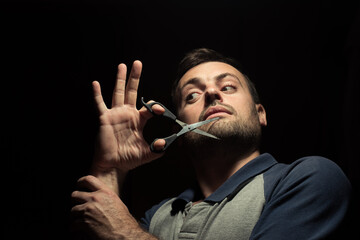 bearded man with scissors on a dark background