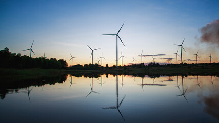 Powerful wind turbine farm for pure energy production on beautiful sunset sun setting behind wind...