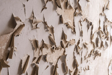Paint peeling off the wall. Wall with flaking paint. Cracks in the white paint