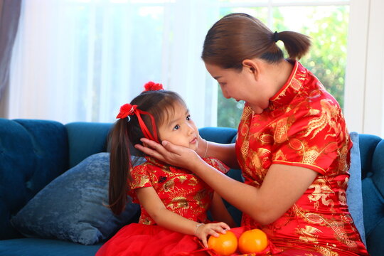 Happy Asian little daughter give auspicious orange to mother on Chinese new year day