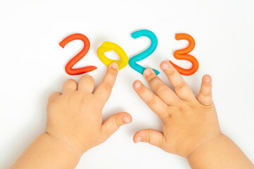 Child's hands playing with figurine 2023 of plasticine on white background. Holiday Art Activity...