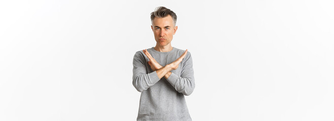 Image of angry middle-aged man looking serious, making cross gesture to stop something bad, telling...