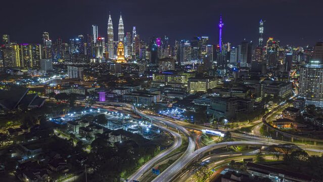 Aerial time lapse overlooking a busy roundabout and city streets against a city skyline in the background at night with city lights in Kuala Lumpur, Malaysia. Prores 4KUHD