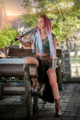 Woman warrior in armor in the old city. A viking girl with pigtails stands in the courtyard of the castle and holds a sword and shield in her hands.