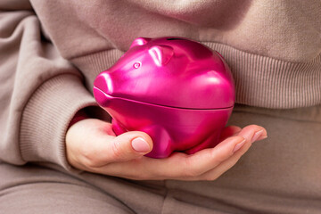 Woman hand holding bright pink pig money box close up. Economy, budget and savings concept.