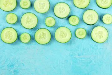 Fresh cucumber slices on a blue background with copy space, overhead shot
