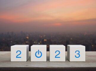2023 start up business icon on white block cubes on wooden table over blur of cityscape on warm...