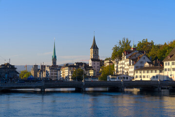 Naklejka na ściany i meble Beautiful cityscape of the old town of Zürich with church towers and Limmat River in the foreground on a sunny late summer morning. Photo taken September 22nd, 2022, Zurich, Switzerland.