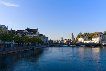 Fototapeta na wymiar Beautiful cityscape of the old town of Zürich with church towers and Limmat River in the foreground on a sunny late summer morning. Photo taken September 22nd, 2022, Zurich, Switzerland.