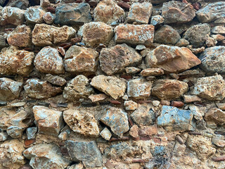 Background, texture, stone wall of round stones cobblestones bricks natural surface natural sharp convex rough stone cobblestone with cracks