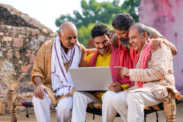 Indian villagers setting at in front of home and using laptop.