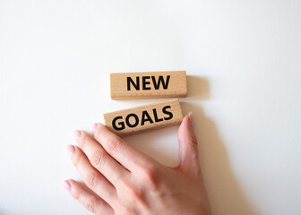 New goals symbol. Wooden blocks with words New goals. Beautiful white background. Businessman hand. Business and New goals concept. Copy space.