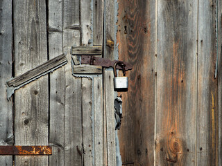 the old barn is locked with a lock hanging on the wooden door. wooden agricultural hangar. texture of old wood.