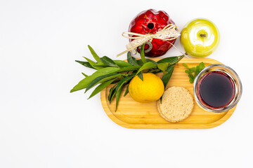 Rosh hashanah holiday jewish new year, white background with pomegranate, apples, tangerine on a branch, traditional bread and a glass of red wine on a wooden tray.