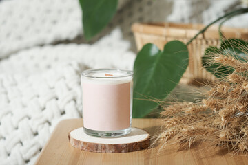soy wax candle in a glass on bedtable with dry whey ears decor. home scents, aroma candles for cozy ambient house.