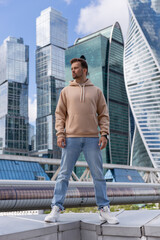 City portrait of handsome hipster guy with beard wearing beige blank hoodie or sweatshirt with space for your logo or design. Mockup for print