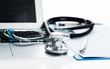 Stethoscope with clipboard and laptop on desk