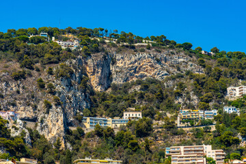 Obraz premium Residential area rising above harbor beach onshore Azure Cost of Mediterranean Sea in Villefranche-sur-Mer resort town in France