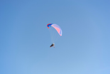 A paraglider with a sled in the blue sky. Winter fun. - 552772434