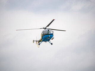 Light utility and trainer helicopter flying against a cloudy sky. Airshow demonstration.