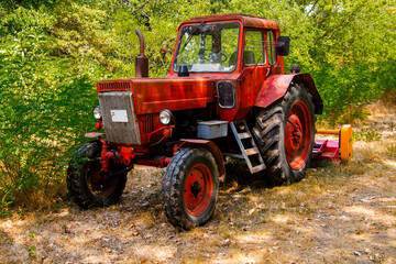 Old, retro red tractor in a forest