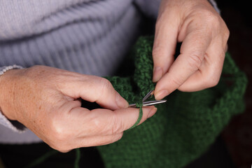 Woman knits with knitting needles from yarn. Concept of cozy knitting at home