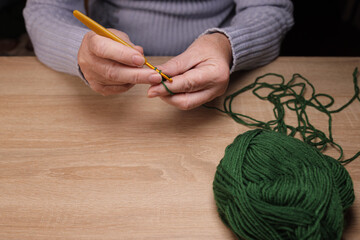 Close-up Hands of woman knits a woolen product by a crochet. Homemade clothes concept