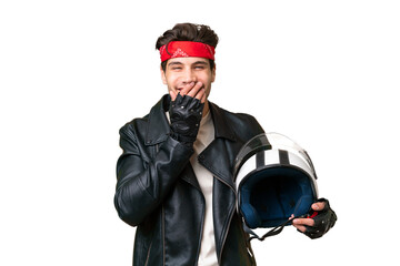 Obraz premium Young caucasian man with a motorcycle helmet over isolated background happy and smiling covering mouth with hand