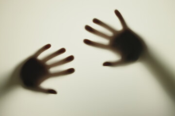 Blurred shadows of hands behind frosted glass, concept of nightmares, horror, domestic violence