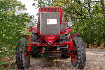 Old, retro red tractor in a forest