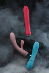 Silicone sex toys in puffs of smoke on a black background Sexual Clitoris Massager for Women Erotic toy for fun Sex gadget and masturbation device Place for text Sex shop concept Dildo Vibrators - obrazy, fototapety, plakaty