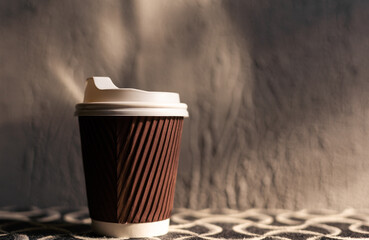 A takeaway paper cup placed on a black wooden table. This photo is suitable for use as a mockup to put your logo or design on it.