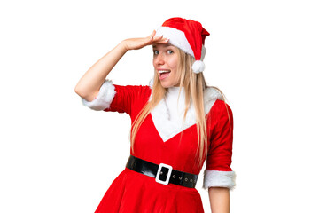 Young blonde woman with christmas hat over isolated chroma key background doing surprise gesture while looking to the side