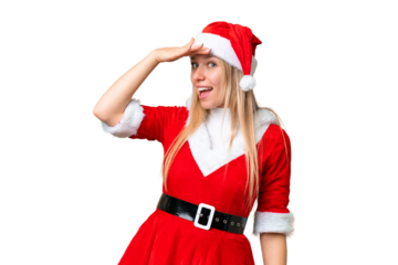Young blonde woman with christmas hat over isolated chroma key background doing surprise gesture while looking to the side