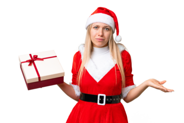 Young blonde woman with christmas hat and holding a gift over isolated chroma key background making doubts gesture while lifting the shoulders