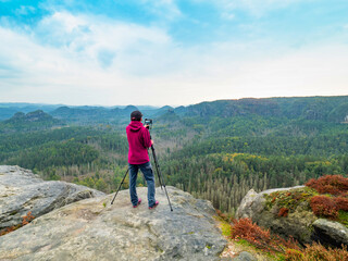 Female tourist with camera on tripod taking travel picture mountain peak.