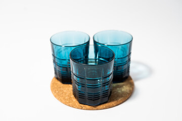 Blue glass cups for whiskey and any drink on a cork stand on a white background